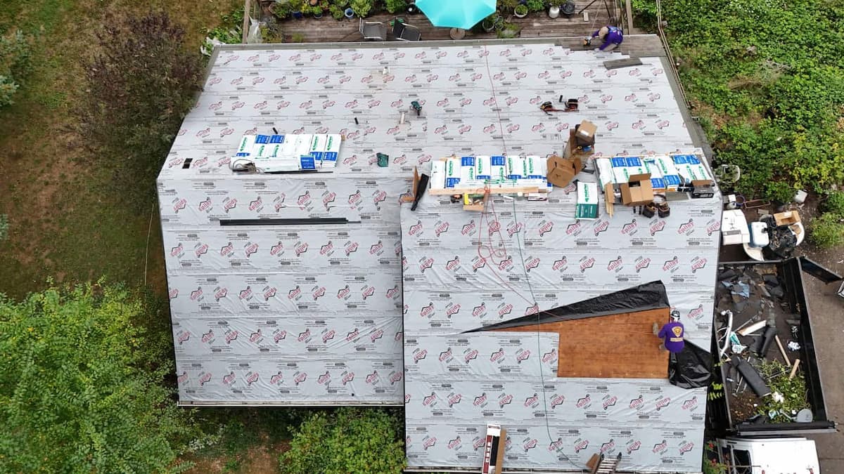 Complete roof replacement in progress on a suburban home with new architectural shingles being installed