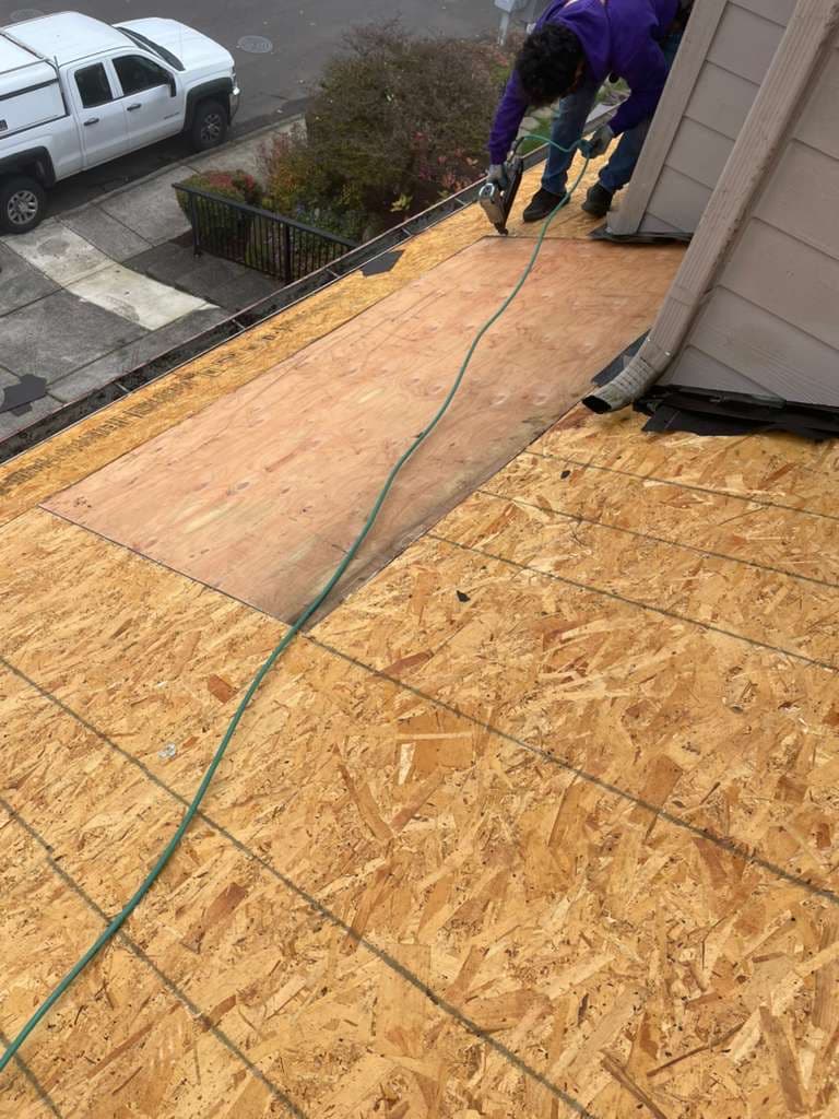 Professional roofer replacing damaged asphalt shingles on residential roof