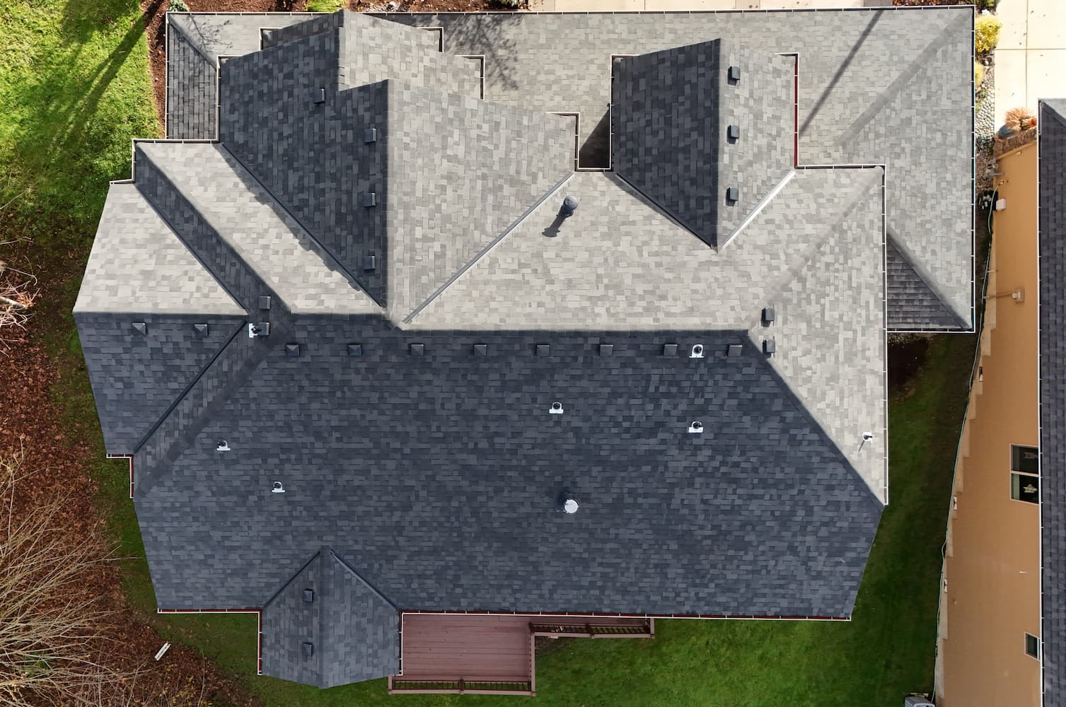 Newly installed dark architectural shingle roof on a well-maintained suburban home with green lawn